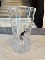 Front view of clear plastic beverage dispenser with spigot attached