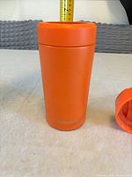 Full view of orange FrostBuddy tumbler standing upright