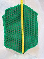 large green and red crocheted placemat with tape showing length ~16 in.