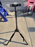 Full view of Ultimate Support tripod guitar stand standing on pavement