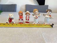 front view of all five figures with measuring tape for scale
