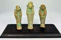 Front view of three faience ushabti figures on hardwood base