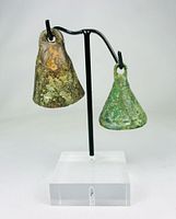 Front view of two bronze bells on stand showing patina and form