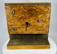 Front view of wooden mortise lock on stand with screws and key inserted