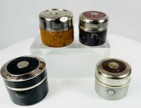 Four closed cylindrical inkwells showing exterior finishes