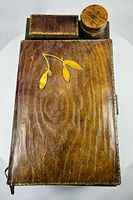 Top view of closed writing slope showing leather grain, gilt leaf motif, border tooling, inkwell cap and accessory box