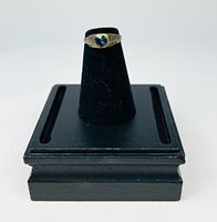 Ring on black stand showing bezel engraving and patina