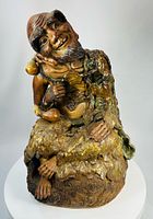 Front view of glazed terracotta Jigong figure on rocky base showing facial expression, gourds and vine leaves