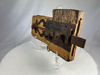 Angled view showing wooden lock, scrolled iron plate, sliding bar and weathered paint