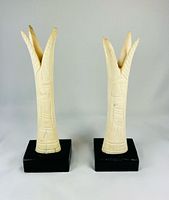 Front view of both carved bone candlestick holders on black bases