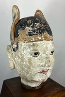 Front left view showing facial features, pigment remnants, wooden base