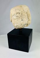 Front three-quarter view of limestone Imsety head on black base