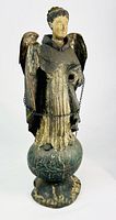 Front view of carved wooden angel statue on orb base with chain and cross visible