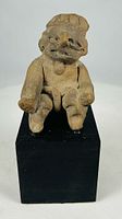 Front view of seated terracotta figure on base