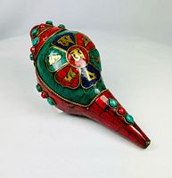 Left-side view showing red lacquer nose, green lacquer body, stone cabochons and lotus medallion