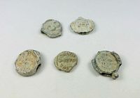Top view of all five corroded tokens showing encrustation and partial legends