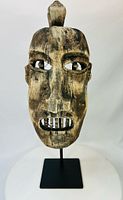 Frontal view of carved hardwood mask showing eyes, nose, mouth, patina