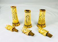 Three bone containers with lids removed, showing scrimshaw patterns and wooden plug ends