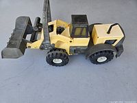 Side view of yellow and black Tonka front-end loader toy truck showing cab, loader arms and bucket