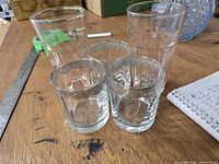 Two tall pink depression glass tumblers and three short silver-etched tumblers on tabletop
