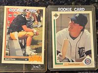 Front view of both rookie cards in plastic sleeves: Brett Favre Star Rookie #13 football and Travis Fryman rookie baseball card