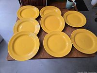 Eight yellow dinner plates on table