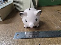 Front view of pink Goebel piggy bank beside ruler