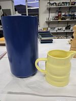 Yellow jug beside blue cylindrical vase front view