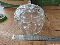 front view of clear glass pumpkin jar next to ruler