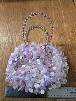 Front view of round lavender sequin handbag with ruler showing approx. 6 in. size