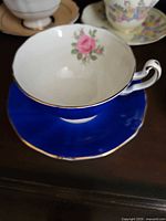Teacup interior showing pink rose, cobalt exterior, gold rim
