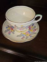 Teacup resting in saucer showing floral pattern and gold trim