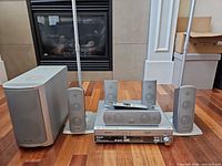 Full system group shot showing receiver, subwoofer, five speakers with stands, remote