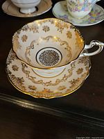 Teacup resting on saucer showing interior filigree and scalloped gold rim