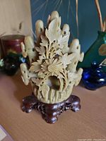 Front view of carved soapstone floral sculpture on wooden stand