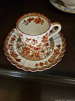 teacup on saucer showing pattern, gilt trim, scale