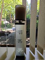 Full view of frosted glass candle holder with wax candle on top