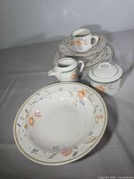 front view showing serving bowl, stacked plates, cup on saucer, creamer and sugar bowl