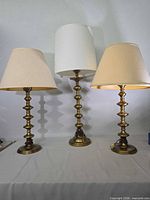 Front view of three brass table lamps with shades
