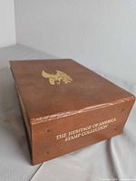 Closed brown faux-leather album with gold eagle, spine text visible