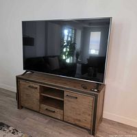 Front view of wood and metal TV stand with two side cabinets, centre shelves and drawers