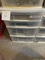 Front view of four-drawer plastic storage unit showing translucent drawers and contents