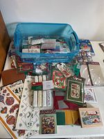 Overview of blue tote (not included) atop table showing paper, trim rolls, stickers, embellishments, glass ornaments and tower drawers nearby