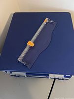 Closed blue storage case with paper trimmer on top