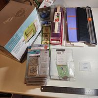 Lot overview showing boxed Cuttlebug, die and folder packs, Stampin' Up! set, three paper trimmers