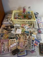 Table covered with various packaged scrapbooking supplies and yellow basket of jars