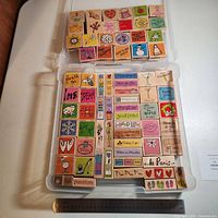 Open storage case displaying two layers of wood-mounted rubber stamps