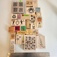 Front view of 31 wooden rubber stamps laid out with ruler for scale