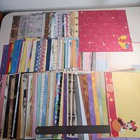 Wide view of multiple stacks of patterned and Disney character scrapbook paper with ruler for scale