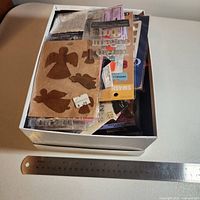 Box showing multiple unopened embellishment packs with ruler for scale